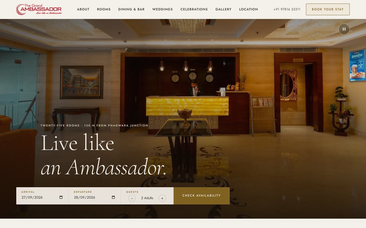 The Grand Ambassador’s home page on a laptop: the lobby, ‘Live like an Ambassador’, the booking bar, and the phone number and Book your stay in the header.